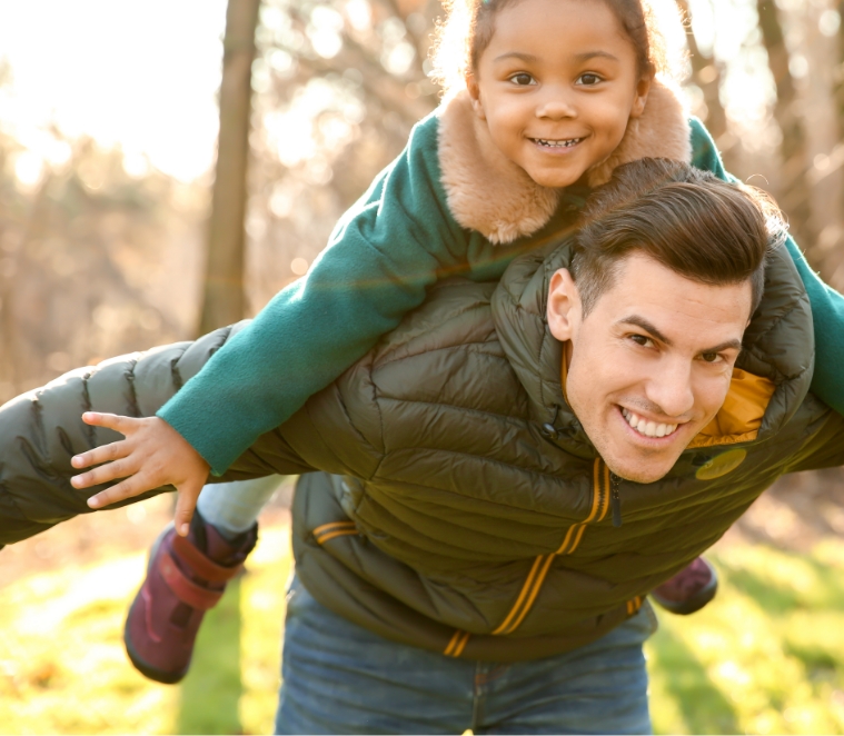 A father carrying a smiling child on his shoulders